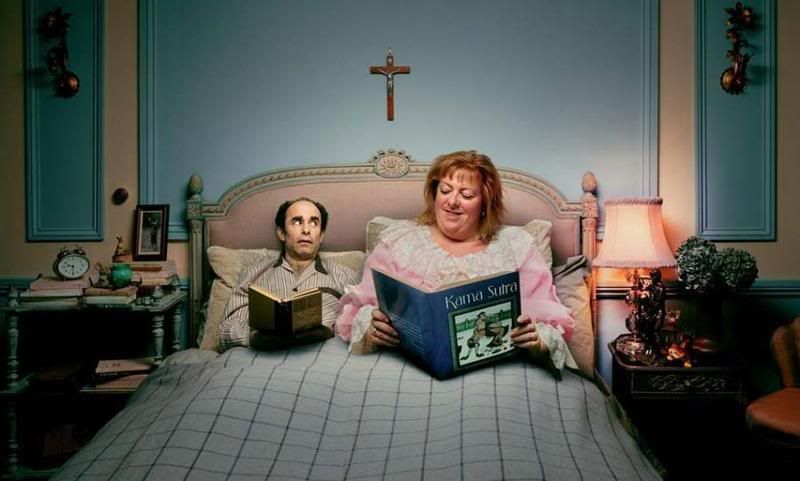 The big wife is enjoying a Kama Sutra book while thin husband looks over