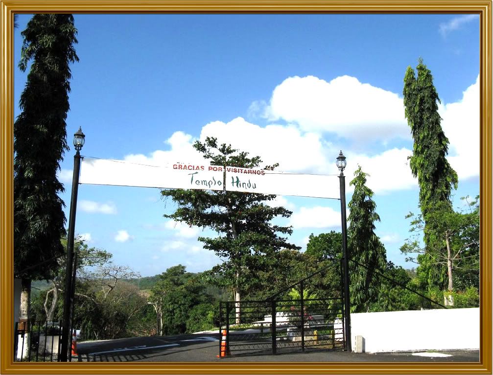View of the main entrance gate to the premises of the Hindu Temple. The sign reads, Thank you for visiting us - Hindu Temple. Notice the lush vegetation around the area of the temple.