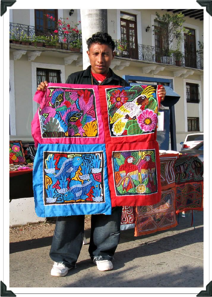 Photograph of a Kuna young man proudly exhibiting four brightly-colored molas.
